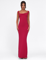 A woman stands against a white background wearing the TIGERMIST ZITA Dress - Red : Salsa : Deep Red, a sleeveless bodycon maxi dress with a slight cowl neckline, styled with black open-toe heels and her dark hair in a center-parted updo.
