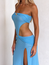A woman models the TIGERMIST KYNLEE DRESS in sky blue, featuring a strapless cut, gold accents, and a high slit, against a white background. Her face is not visible.